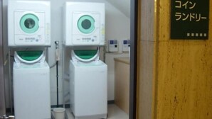 A laundry room with two stacked washing machines and a sign in Japanese. - Hamada NEW Castle Hotel (Hamada)