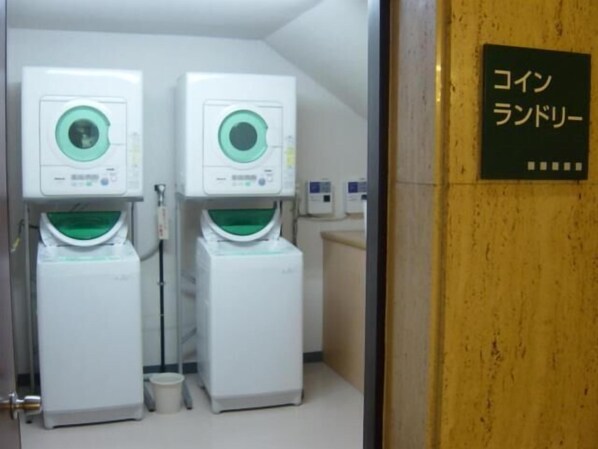 A laundry room with two stacked washing machines and a sign in Japanese.
