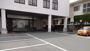 A parking lot with marked spaces and a building entrance with columns. - Hamada NEW Castle Hotel (Hamada)