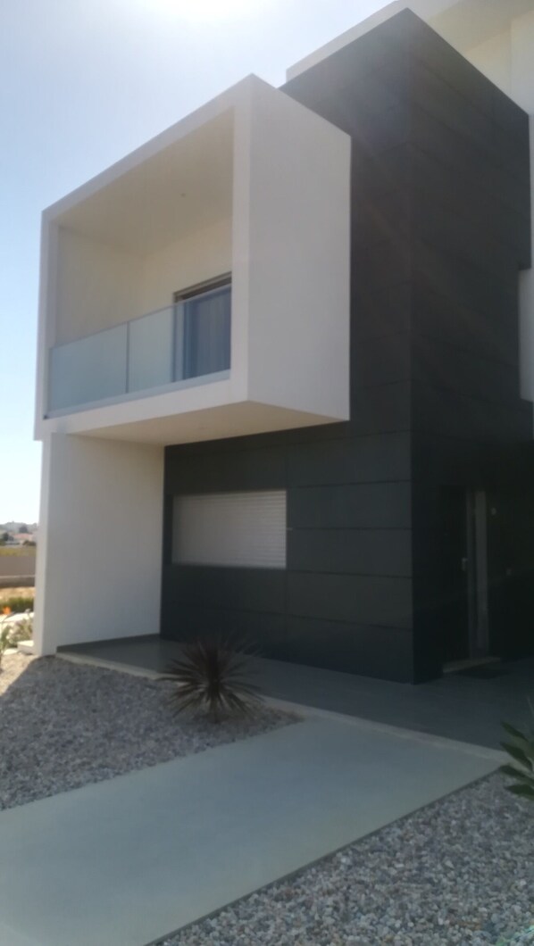 A modern two-story building with a flat roof, large windows, and a minimalist design.