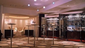 A bar area with a patterned carpet, round tables, and a bar stocked with bottles. - Mizusawa Grand Hotel (Oshu)