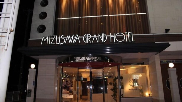 The exterior of Mizusawa Grand Hotel with a prominent entrance and a sign above the door. - Mizusawa Grand Hotel (Oshu)