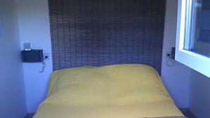 A bed with a yellow bedspread and a floral-patterned pillow. - shed in a property close to the countryside (Pélissanne)