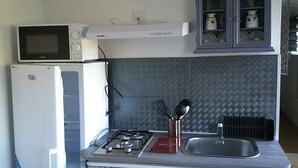 A compact kitchen with a microwave, refrigerator, gas stove, and a cabinet with dishes. - shed in a property close to the countryside (Pélissanne)