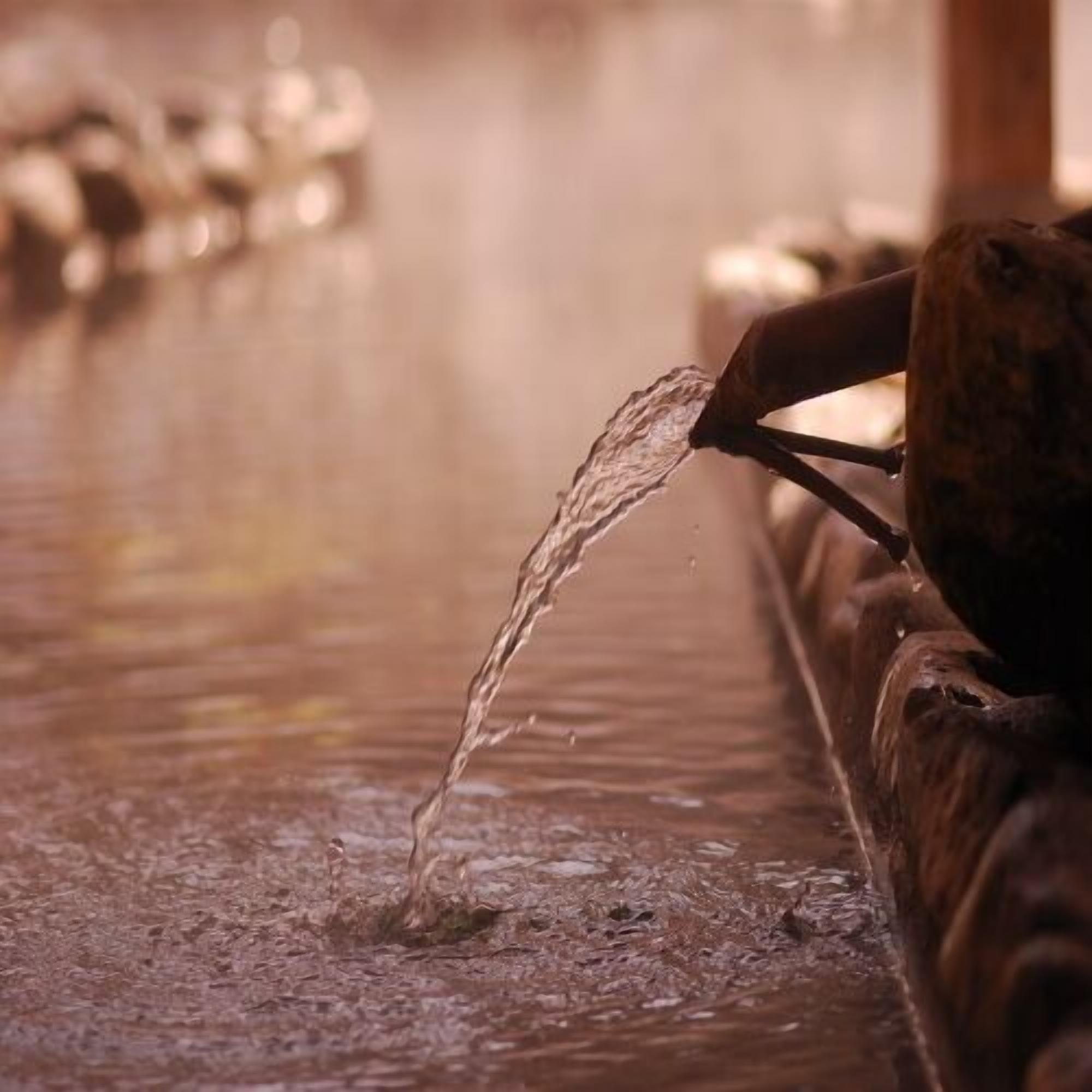 Una fuente de agua con un arroyo que fluye sobre una estructura de madera.