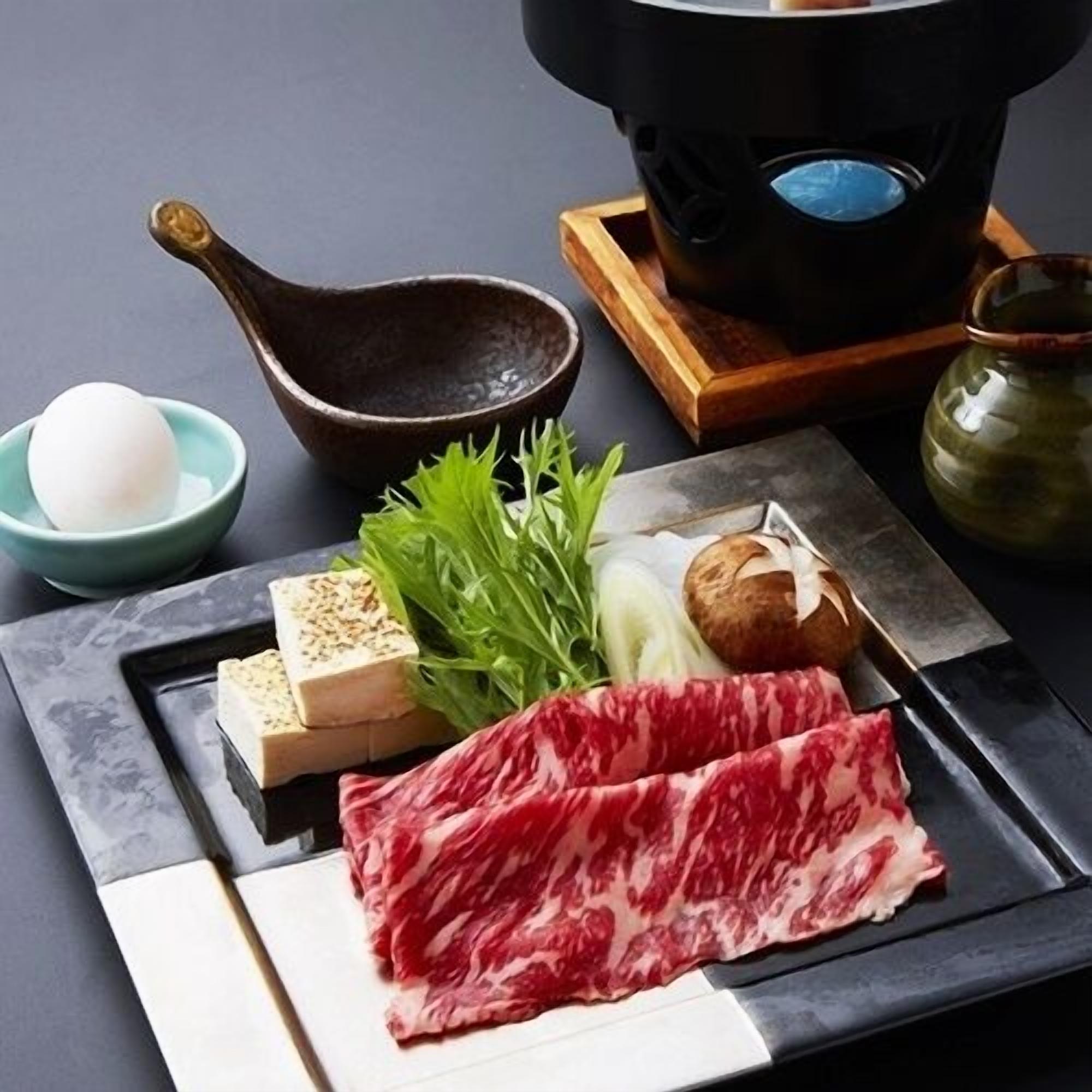 A dining setup with a plate of sashimi, a bowl of soup, and a teapot.