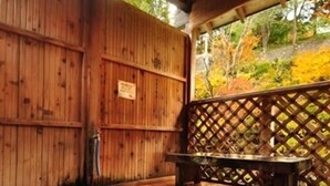 Un bain à remous en bois, doté d’un banc, entouré de murs en bois et d’une clôture en treillis.