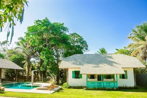 A house with a swimming pool, surrounded by lush greenery and palm trees. - Casa Jequitibá Rosa (Porto Seguro)