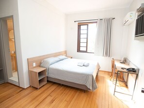 A bedroom with a bed, bedside table, desk, and a window with curtains. - Hotel Dom Rafael Business (Santa Maria)