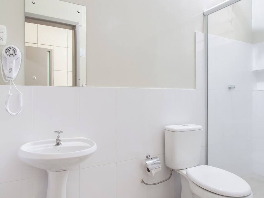 Un baño con lavamanos, inodoro y cabina de ducha de vidrio.