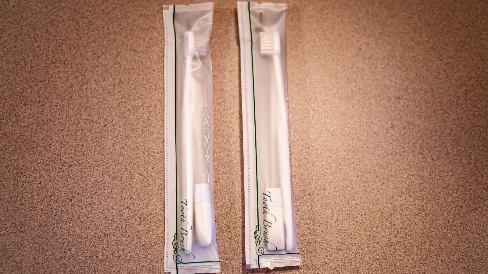 Two toothbrushes in their packaging on a carpeted floor.