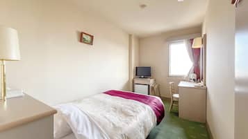 A hotel room with a bed, a desk, a television, a chair, and a window with curtains.