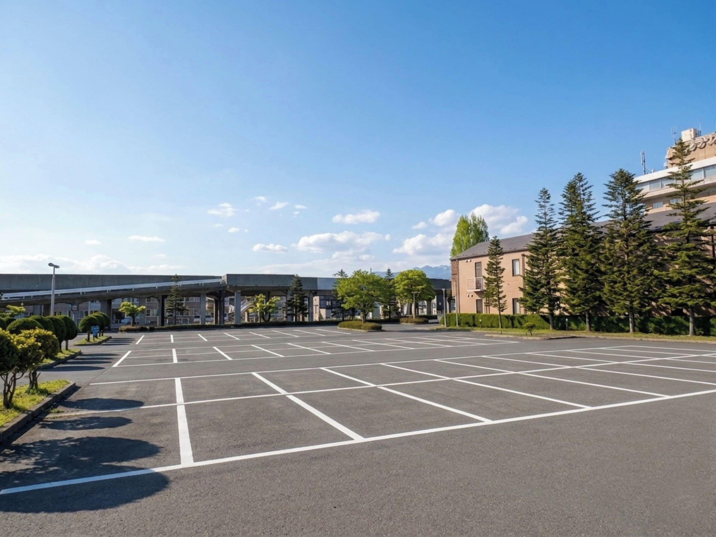 A parking lot with marked spaces, a building with a flat roof, and a clear sky.