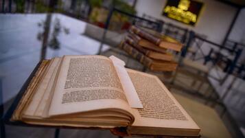 Un libro abierto sobre una mesa en un espacio público, con estanterías al fondo.