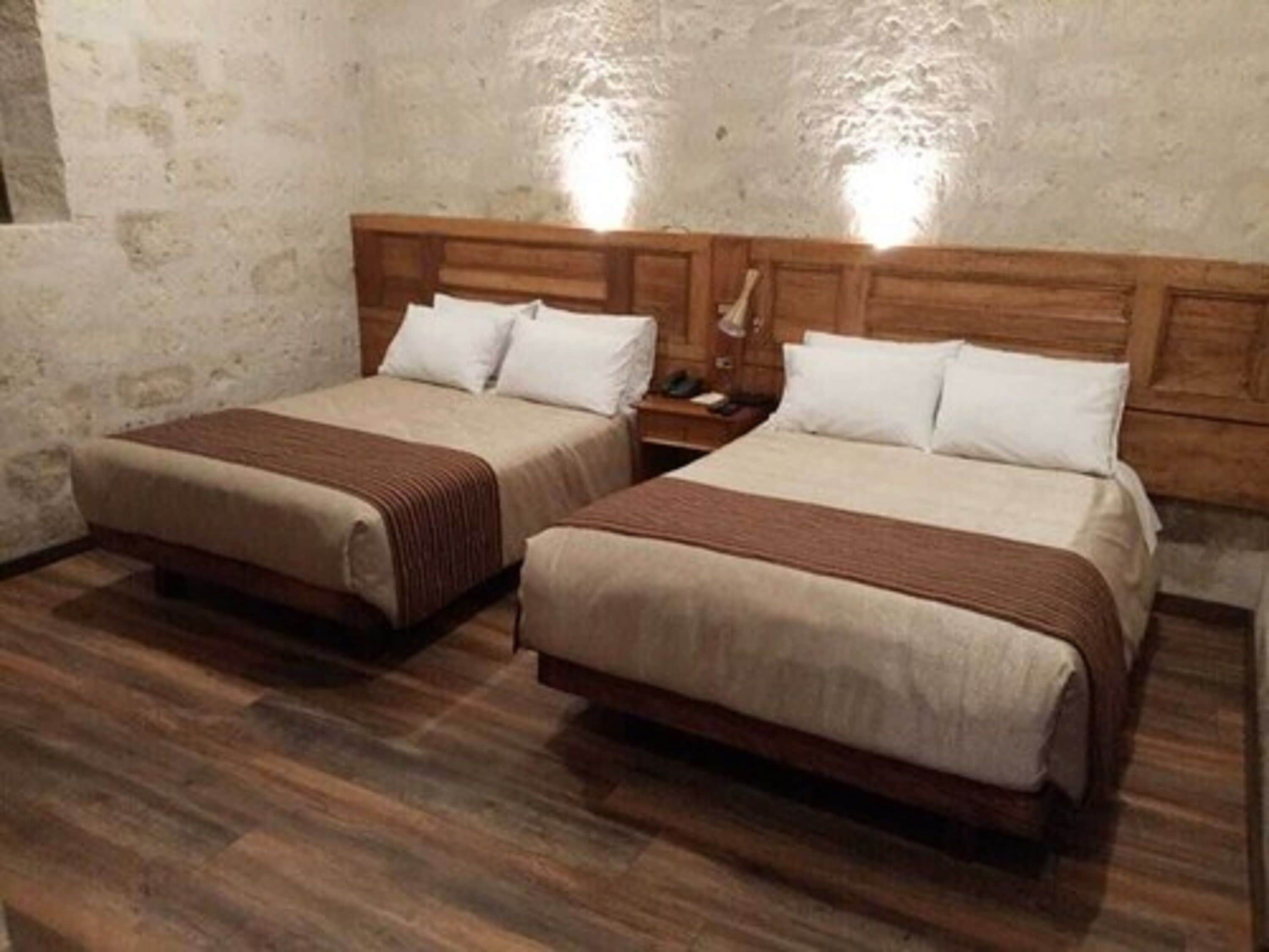 Twee enkele bedden met houten hoofdborden, een houten vloer en een structuurwand.