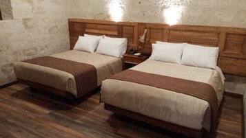 Two single beds with wooden headboards, a wooden floor, and a textured wall.