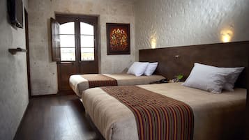 Una habitación de hotel con dos camas, una puerta de madera, un cuadro y un televisor en la pared.
