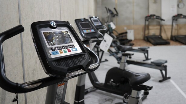 A row of stationary bikes in a gym with a marble wall and a chandelier. - Yuzawa Royal Hotel (Yuzawa)