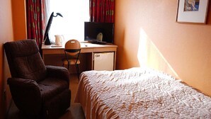 A hotel room with a bed, a desk with a computer, a chair, and a small refrigerator. - Yuzawa Royal Hotel (Yuzawa)