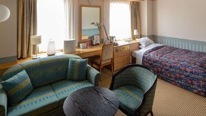 A hotel room with a sofa, a chair, a bed, a desk, and a mirror. - Yuzawa Royal Hotel (Yuzawa)