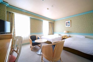 Een hotelkamer met een bed, een televisie, een eettafel met stoelen, en een kleine ronde tafel met stoelen.