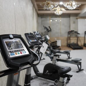 A row of stationary exercise bikes with digital displays in a room with a chandelier. - Yuzawa Royal Hotel (Yuzawa)