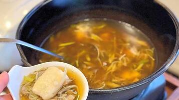 A pot of soup with noodles and a dumpling on a stove.