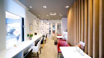 A modern interior with a long counter, seating area, and a view through a window.