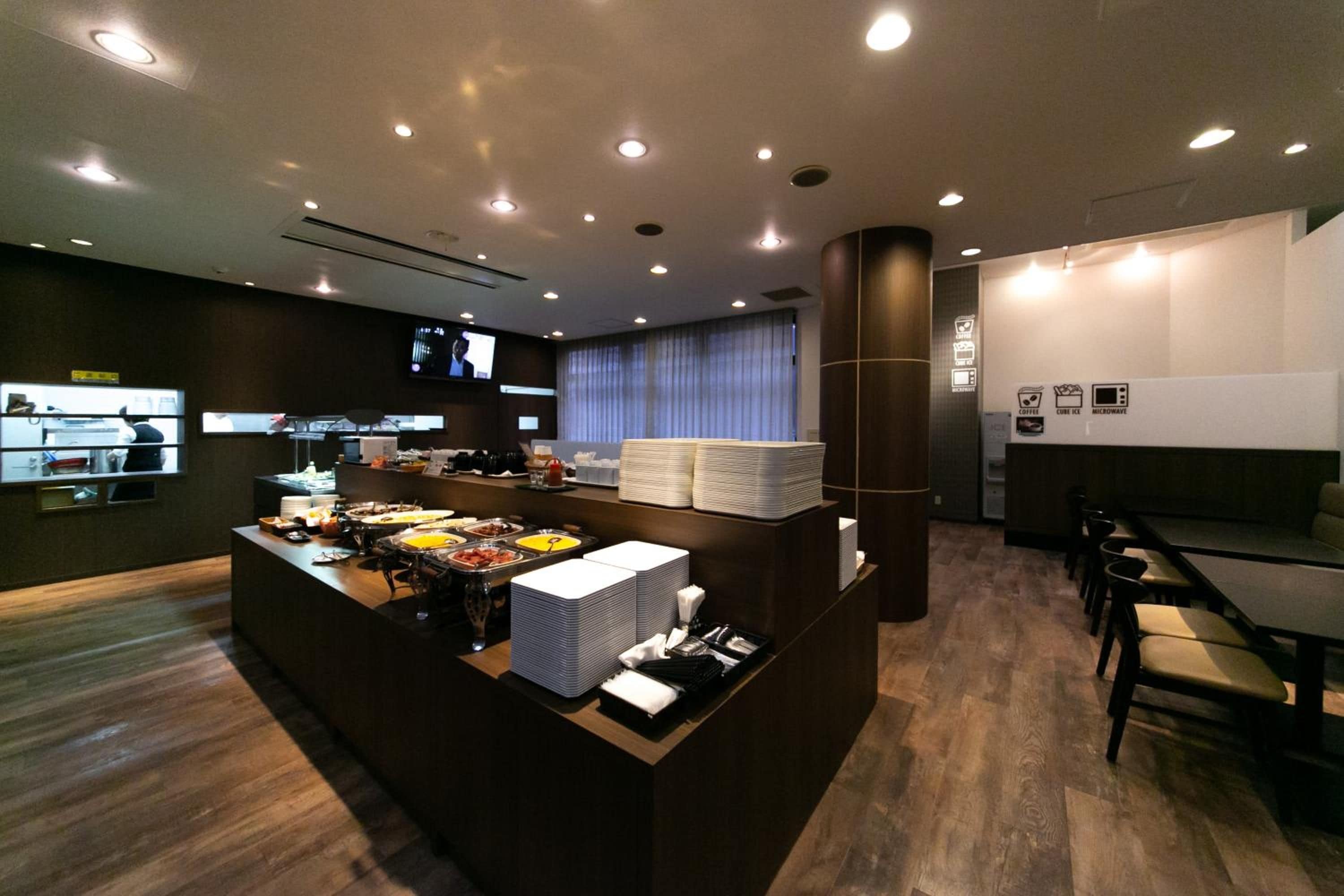 A modern hotel lobby with a reception desk, buffet area, and seating.