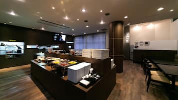 A modern hotel lobby with a reception desk, buffet area, and seating.
