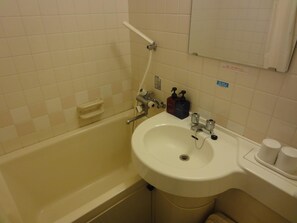 A bathroom with a bathtub, sink, and toilet. There are soap dispensers and a towel rack. - Hotel Elm Regency (Shimizu)