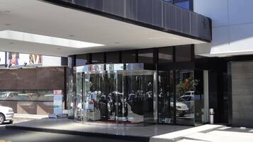 A modern building entrance with a glass door and a covered waiting area.