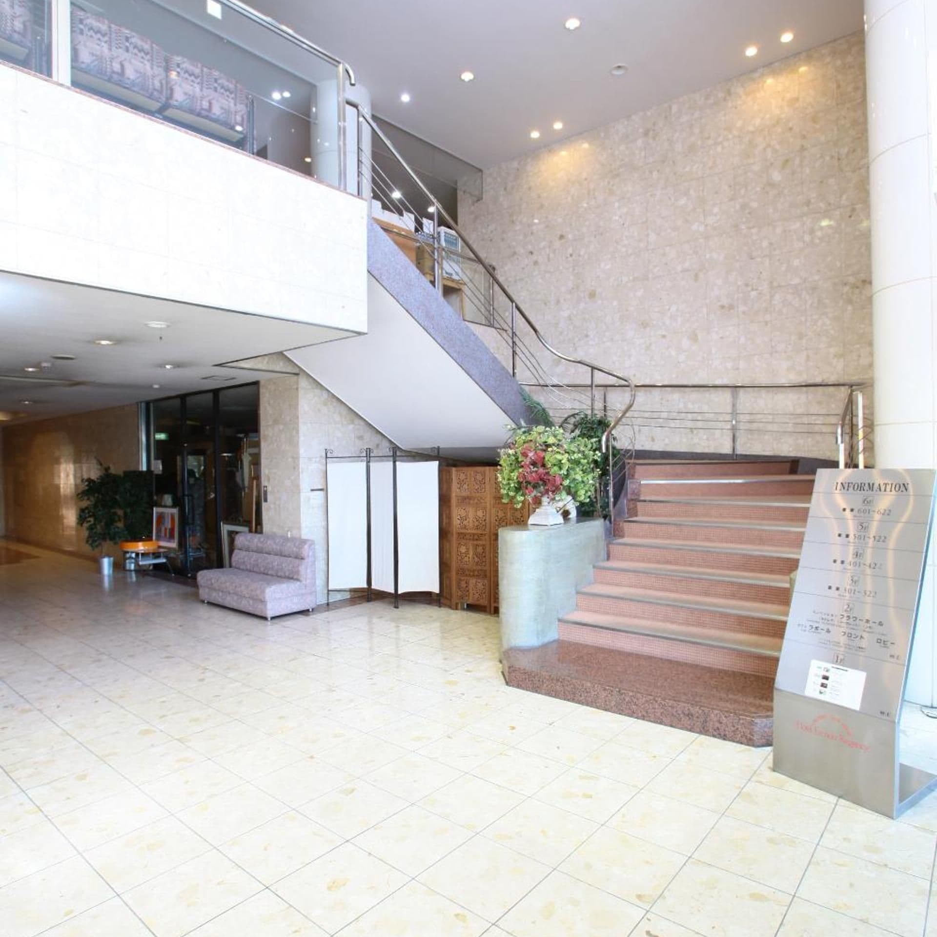 A spacious lobby with a staircase, a reception desk, and a seating area.