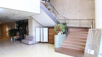 A spacious lobby with a staircase, a reception desk, and a seating area.