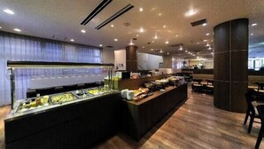 A buffet area with a variety of food options, a seating area with tables and chairs, and a modern ceiling design with recessed lighting. - Hotel Ermou Regency (Shimizu)