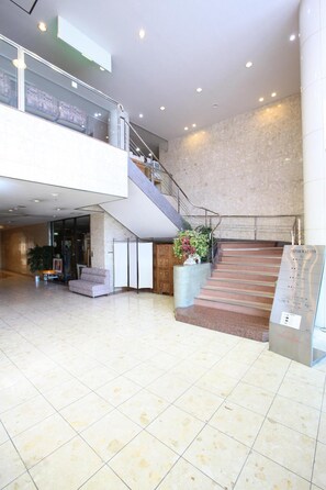 A spacious lobby with a staircase, a reception desk, and a seating area. - Hotel Elm Regency (Shimizu)