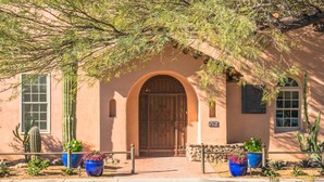 A building with a large wooden door, arched windows, and potted plants.