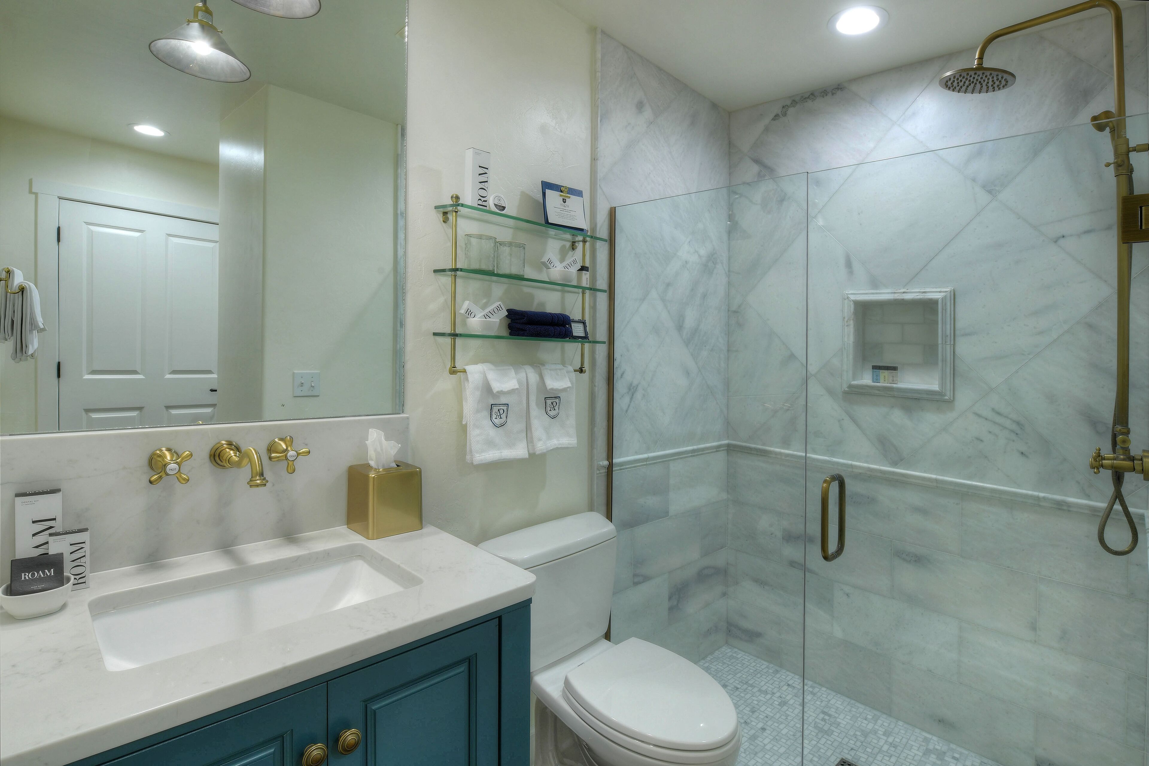 A bathroom with a white sink, a toilet, a glass shower enclosure, and a mirror.