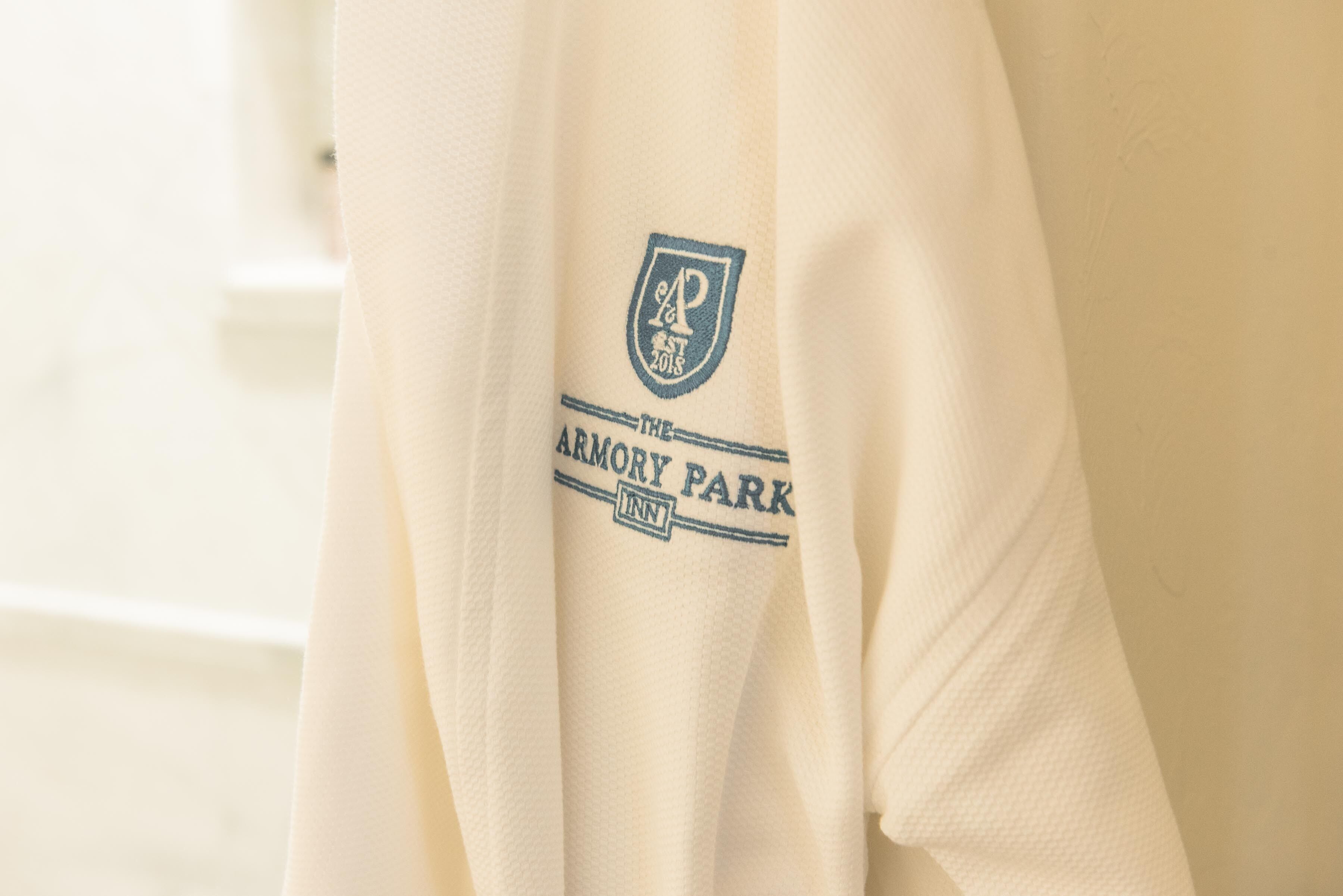 Una prenda blanca con un logotipo y el texto 'The Armory Park Inn'.