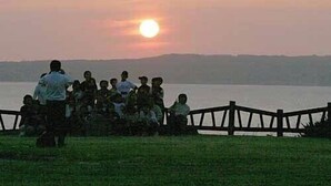 A group of people sitting on a grassy area near a body of water during sunset. - Fureaihouse Sizu NO Sato Sadogashima (Sado)