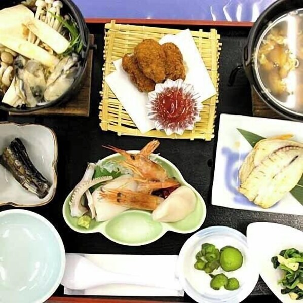 Une variété de plats, notamment des fruits de mer, des légumes et un bol de soupe, disposés sur une table.