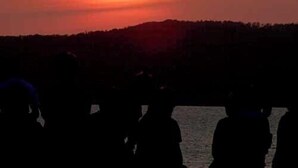 Silhouettes of people against a sunset with a sun visible in the sky. - Fureaihouse Sizu NO Sato Sadogashima (Sado)