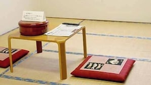 A room with tatami mat flooring, a small wooden table with a red container and a paper on it, and a window with a grid pattern. - Fureaihouse Sizu NO Sato Sadogashima (Sado)