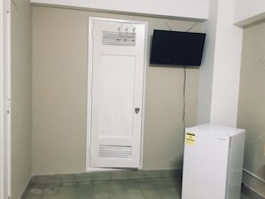 Cozy room with a flat-screen TV, refrigerator, and tiled floor.