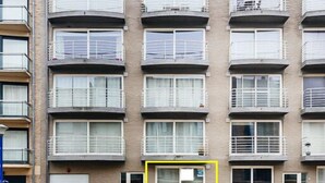 A multi-story residential building with balconies, a gated entrance, and a paved driveway. - Santos Secundo GV01 (Koksijde)