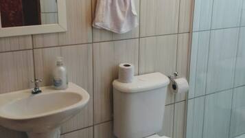 Casa de banho com lavatório, sanita e um pequeno contentor de lixo.