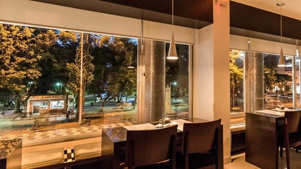 Un restaurante con amplios ventanales que ofrecen vistas a la calle y a los árboles.