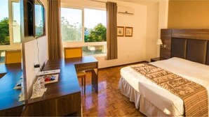 Habitación de hotel con una cama grande, un escritorio y un televisor.
