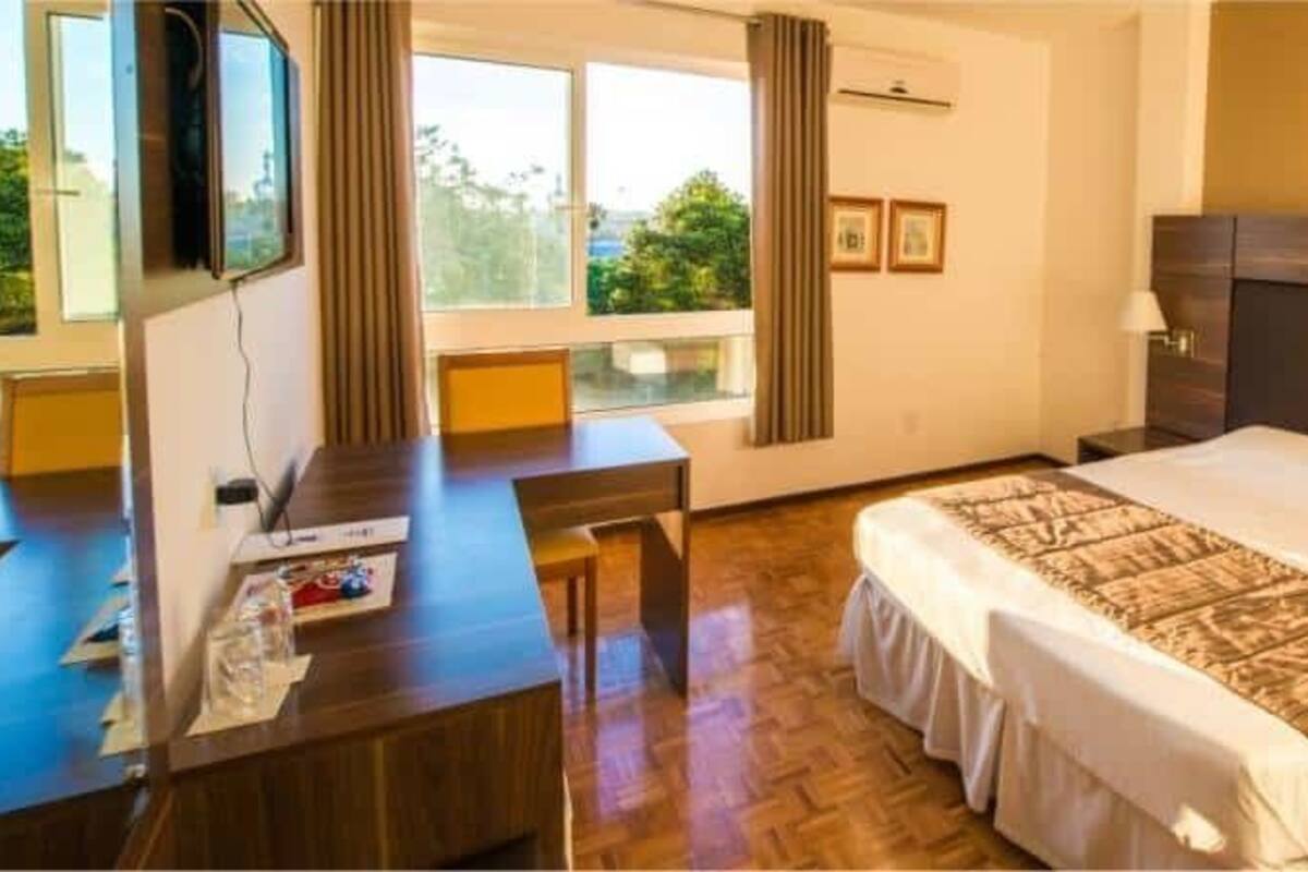 Quarto de hotel com uma cama grande, uma mesa e uma televisão.