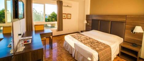Habitación de hotel con una cama grande, un escritorio y un televisor.